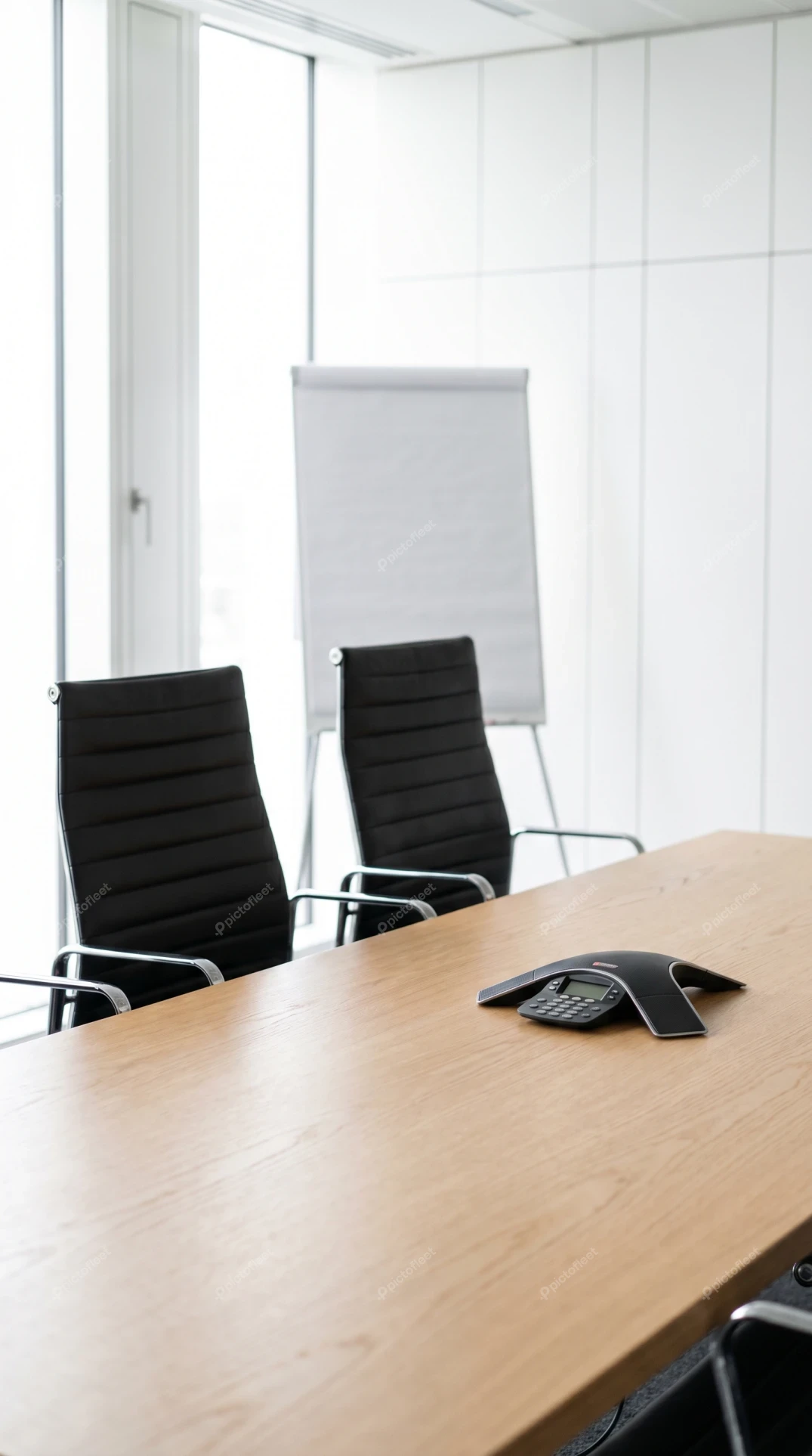 Modern conference room with wooden table and speakerphone