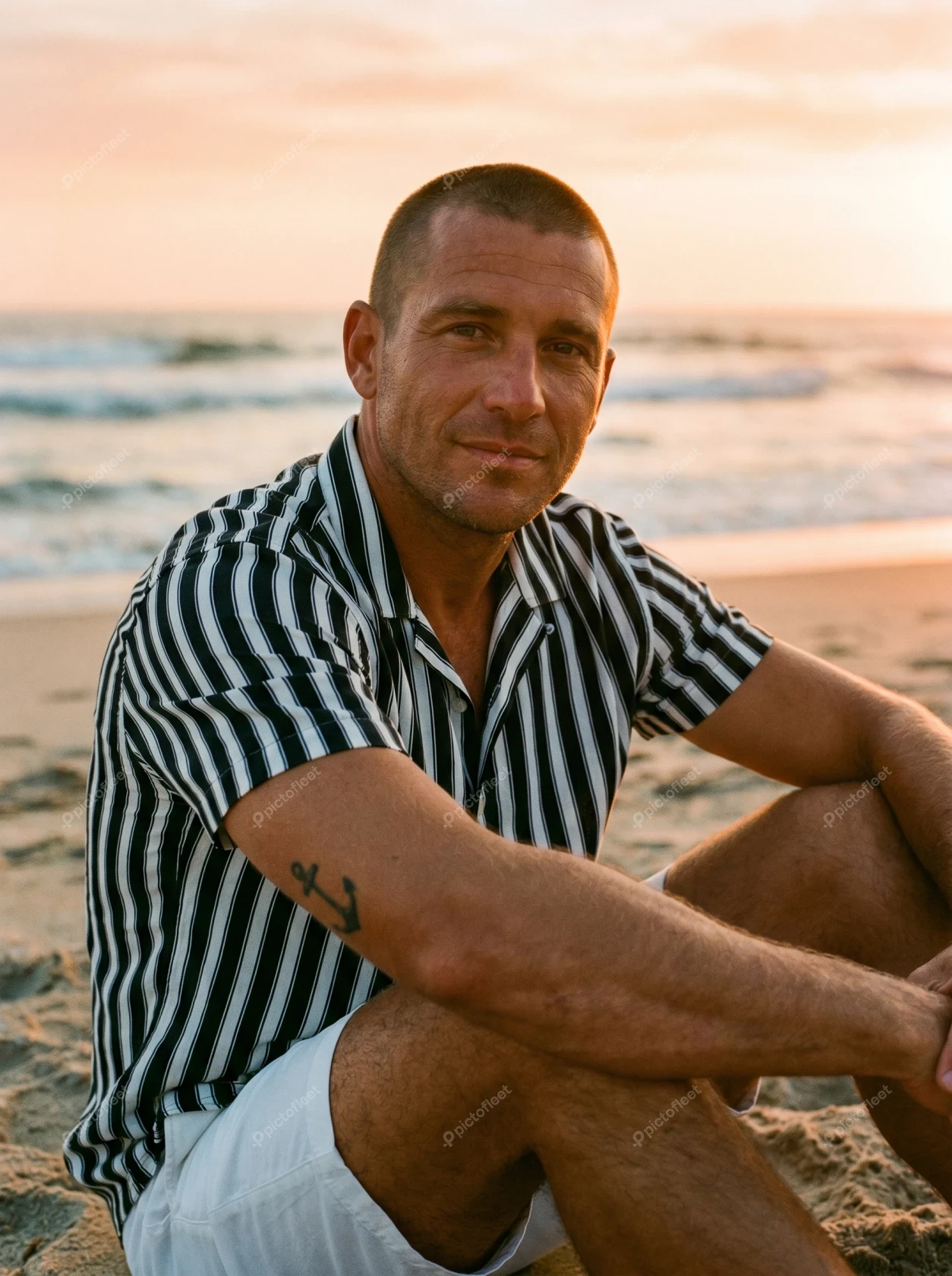 Man sitting on a sandy beach at sunset