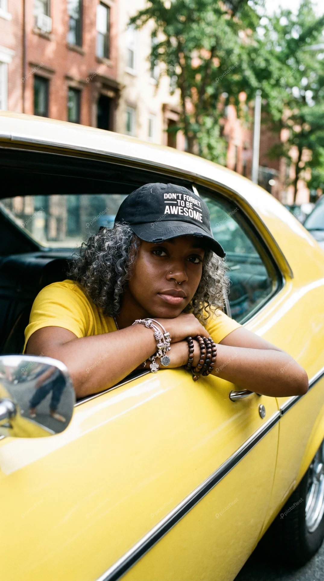 Woman leaning out of window of yellow vintage car