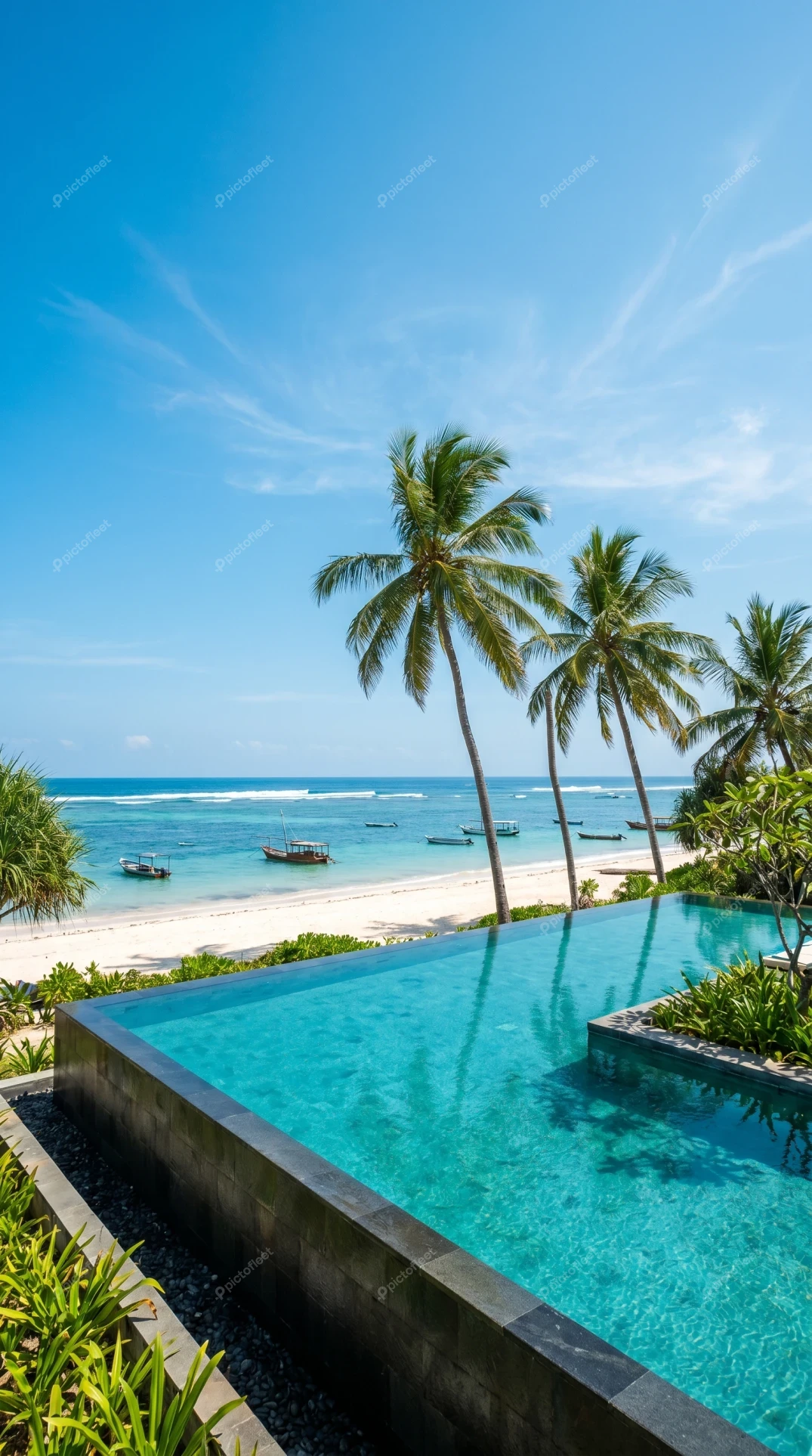 Luxury infinity pool overlooking tropical beach with palm trees
